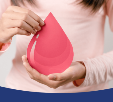 Egy rózsaszín ruhás személy két kézzel tart egy nagy, piros vércsepp alakú papírt, szimbolizálva a vérplazma adományozás fontosságát.